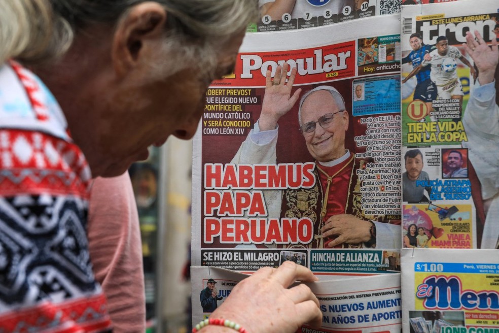Uma mulher olha as primeiras páginas de jornais peruanos celebrando a nomeação do cardeal americano Robert Prevost como o novo Papa Leão XIV em uma banca de jornal no centro de Lima — Foto: CONNIE FRANCE / AFP