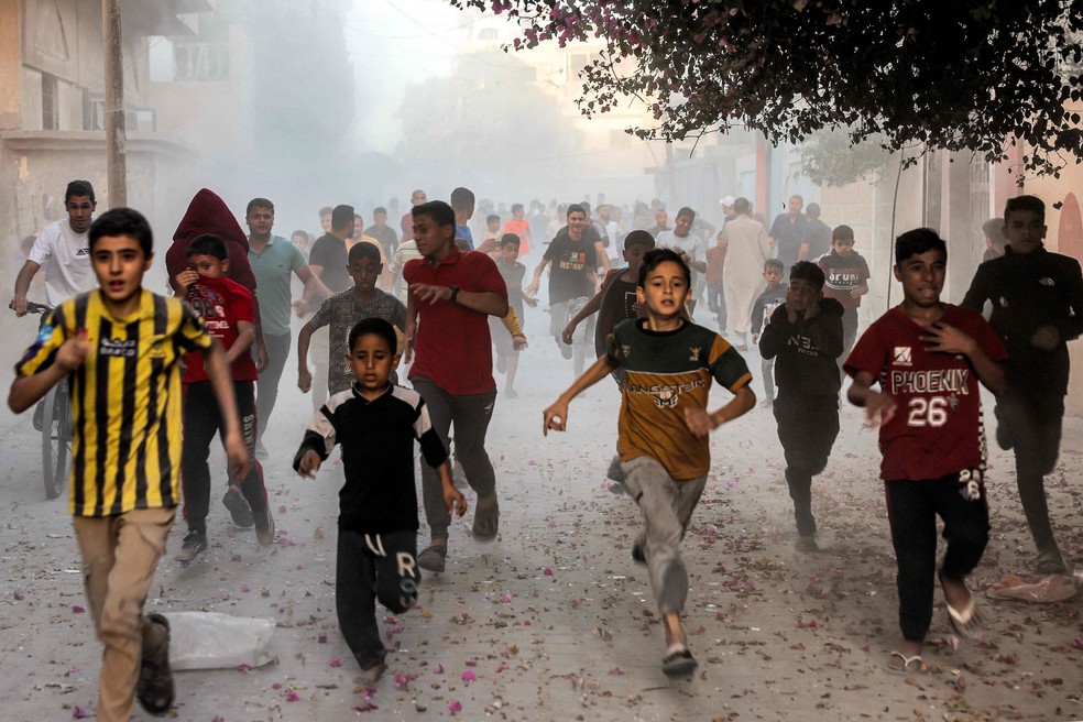 Crianças palestinas fogem de um bombardeio israelense a Rafah, ao sul da Faixa de Gaza, em novembro de 2023 — Foto: AFP
