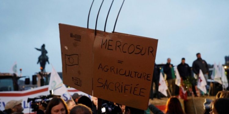 Ativistas do sindicato de agricultores francês FNSEA (Federação Nacional dos Sindicatos de Produtores Agrícolas) seguram um cartaz com os dizeres “Mercosul = Agricultura sacrificada” durante um protesto contra a concorrência desleal e o acordo de livre-comércio do Mercosul, na Place d'Armes do Castelo de Versalhes — Foto: Geoffroy Van Der Hasselt/AFP