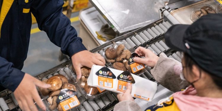 Etiquetagem de produto na área de estoque de uma das lojas do Wumart, rede de supermercados da China — Foto: Yan Cong/Bloomberg