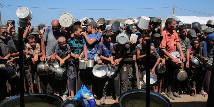 Palestinos aguardam para receber porções de comida de uma cozinha beneficente em Khan Yunis, no sul da Faixa de Gaza — Foto: AFP