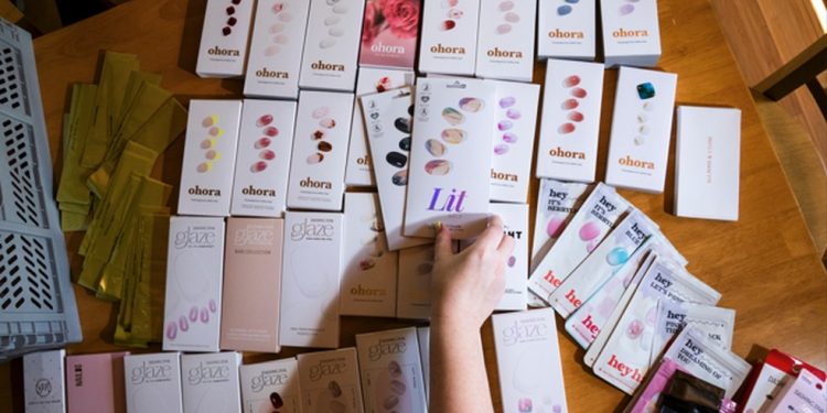 Emily Uhlig com alguns de seus conjuntos de tiras para unhas em casa, em Westhampton, Massachusetts — Foto: Joe Buglewicz/The New York Tims