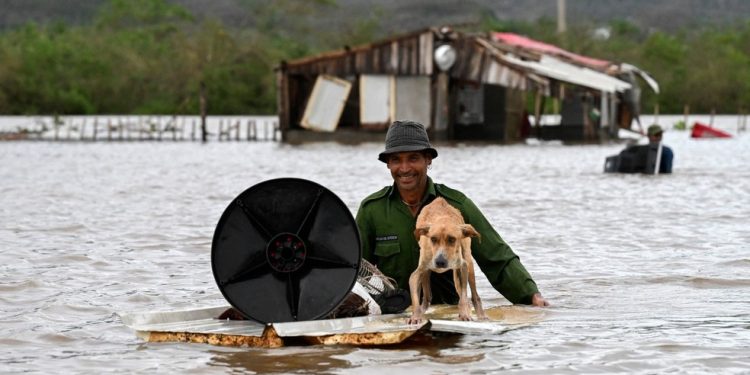 Um agricultor resgata seu cachorro e alguns pertences de sua casa inundada após a passagem do furacão Melissa pela cidade de San Miguel de Parada, na província de Santiago de Cuba, em 29 de outubro de 2025 — Foto: Yamil Lage / AFP