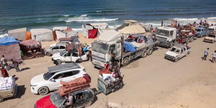 Palestinos carregando pertences chegam a uma trilha costeira a noroeste do campo de refugiados de Nuseirat, enquanto são deslocados para o sul de Gaza após o anúncio israelense de fechar a estrada al-Rashid — Foto: Bashar TALEB / AFP