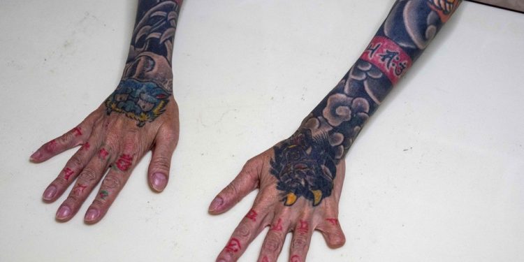 A yakuza aposentada Mako Nishimura mostra seu antebraço coberto por tatuagens de dragão e tigre e a ponta de um dedo faltando, que ela mesma cortou como parte do ritual de autopunição da yakuza por seus erros — Foto: Yuichi Yamazaki / AFP