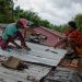 Dois homens consertam o telhado de uma casa após a passagem da tempestade tropical Melissa, antes de se tornar um furacão, em Barahona, na República Dominicana, em 28 de outubro de 2025 — Foto: AFP