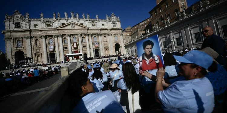 Fiel segura retrato do adolescente Carlo Acutis em frente à Basílica de São Pedro, antes da Santa Missa e da cerimônia de canonização do beato — Foto: Filippo Monteforte / AFP