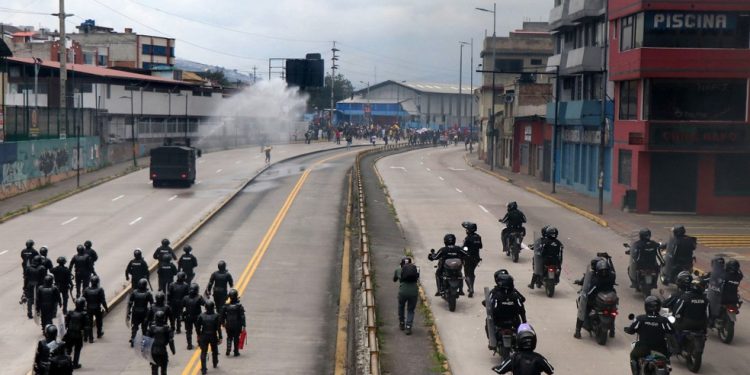 Um caminhão da polícia de choque borrifa água em manifestantes durante uma marcha contra o racismo, a criminalização dos protestos e em apoio à greve nacional convocada pela Conaie enquanto se dirigiam ao parque El Arbolito, em Quito — Foto: Galo Paguay / AFP