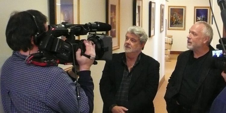 Drew Struzan, à direita, acompanha o depoimento de George Lucas sobre sua obra, em cena de documentário sobre ele — Foto: Divulgação