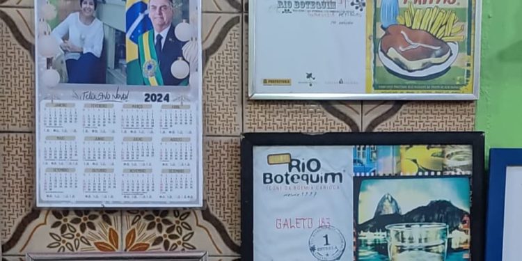 Na parede, pendurado ao lado dos prêmios que o Galeto 183 já recebeu, há um calendário de 2024 é ilustrado com a foto oficial de Jair Bolsonaro e outra de Dona Ana — Foto: Thales Machado