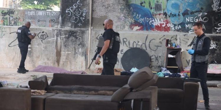 Peritos e policiais examinam o local onde três pessoas em situação de rua foram baleadas — Foto: Fabiano Rocha / Agência O Globo