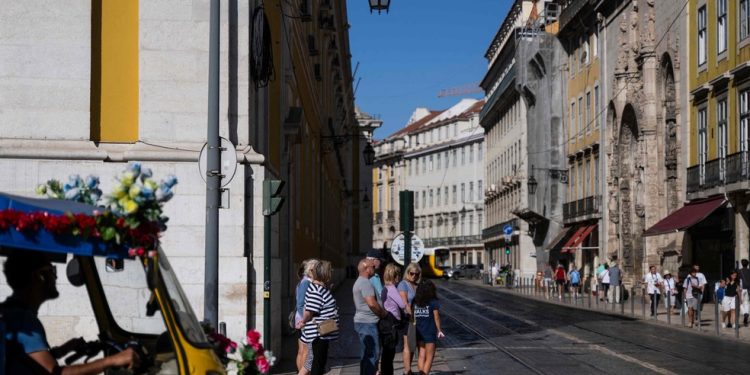 Pedestres e tuk tuk de turismo aguardam para atravessar rua em Lisboa — Foto: Patrícia de Melo Moreira/AFP