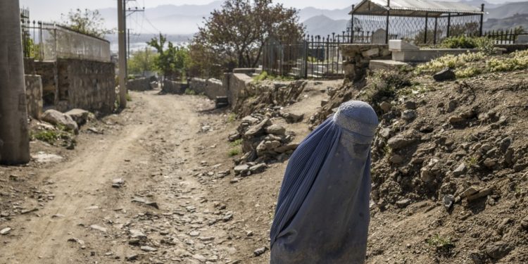 Mulher caminha por uma estrada em Cabul, Afeganistão, em 20 de abril de 2023, com o corpo completamente coberto; regime repressivo do Talibã agora proíbe até as vozes femininas em público — Foto: Jim Huylebroek/The New York Times