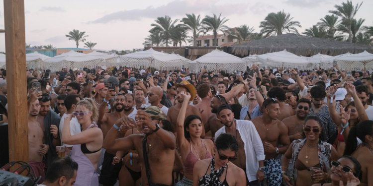 Homens e mulheres, em sua maioria vestidos com trajes de praia, dançam no festival dentro do complexo Almaza Bay — Foto: Fatma Fahmy / New York Times