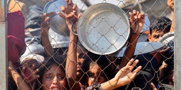 Crianças palestinas imploram por comida em área de ajuda humanitária próxima a Khan Younis, na Faixa de Gaza, em 22 de julho de 2025 — Foto: AFP