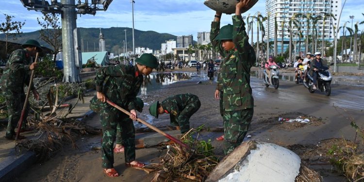 Soldados ajudam a remover os destroços da estrada na área costeira de Quy Nhon, província de Gia Lai, no centro do Vietnã, após a passagem do tufão — Foto: NHAC NGUYEN / AFP