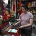 Thitinan Suntisubpoo usa calculadora em sua loja em Banckoc — Foto: Lillian Suwanrumpha/ AFP
