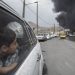 Um menino observa colunas de fumaça subindo de um depósito de petróleo em Teerã, Irã, no domingo, 8 de março de 2026, após ataques noturnos das forças americanas e israelenses — Foto: Arash Khamooshi / New York Times