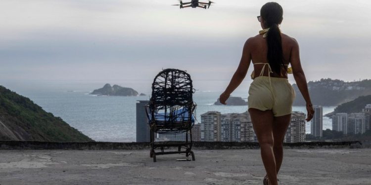 Uma mulher é filmada por um drone para um vídeo nas redes sociais no famoso mirante turístico “Porta do Céu”, na favela da Rocinha, no Rio de Janeiro. — Foto: Pablo Porciúncula/AFP