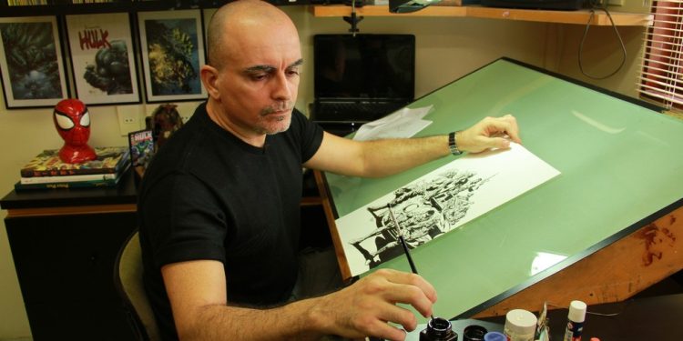 O paraibano Mike Deodato Jr. desenha em sua prancheta: quadrinista ficou conhecido pelos seus traços de personagens da DC e da Marvel — Foto: Divulgação