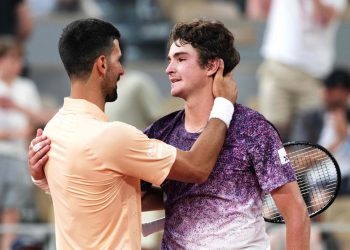O brasileiro João Fonseca (à direita), cumprimenta o sérvio Novak Djokovic ao final da partida de simples masculina do sexto dia do torneio de tênis do Aberto da França, na quadra Philippe-Chatrier, no complexo de Roland-Garros — Foto: Dimitar DILKOFF / AFP