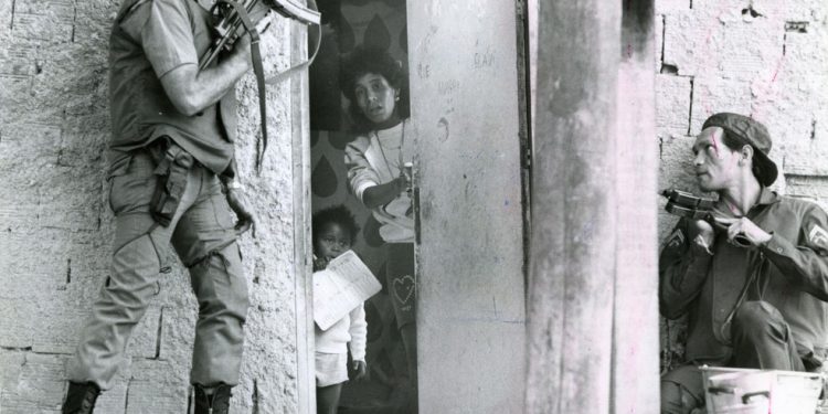 Moradora do Dona Marta entre policiais armados, em 1987 — Foto: Frederico Rozário/Agência O GLOBO