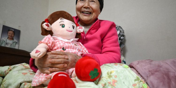 Kim Young-bun, uma idosa sul-coreana que vive sozinha, segurando Hyodol, uma boneca de saúde com inteligência artificial projetada para idosos — Foto: Jung Yeon-Je / AFP