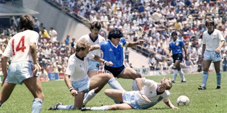 Maradona passa pela marcação de dois jogadores da Inglaterra em jogo na Copa de 1986 — Foto: AFP