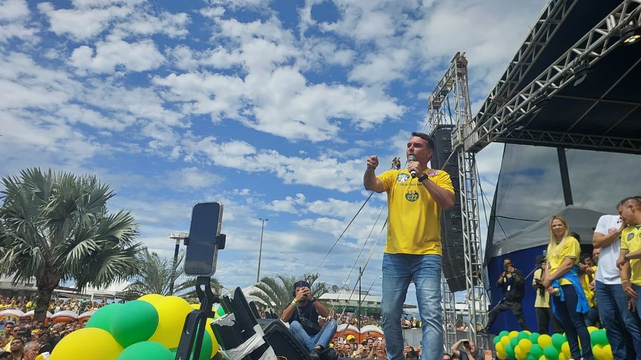 Flávio Bolsonaro 'esconde' Queiroz em palco de evento no RJ, puxa coro contra Moraes e repete que relação com Vorcaro foi 'privada'